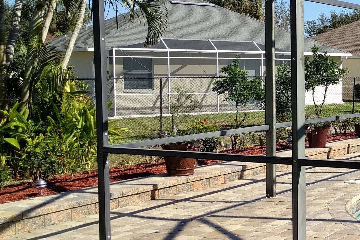 Freshly painted pool cage with bronze DTM coating on a Florida home with sparkling pool and tropical landscaping