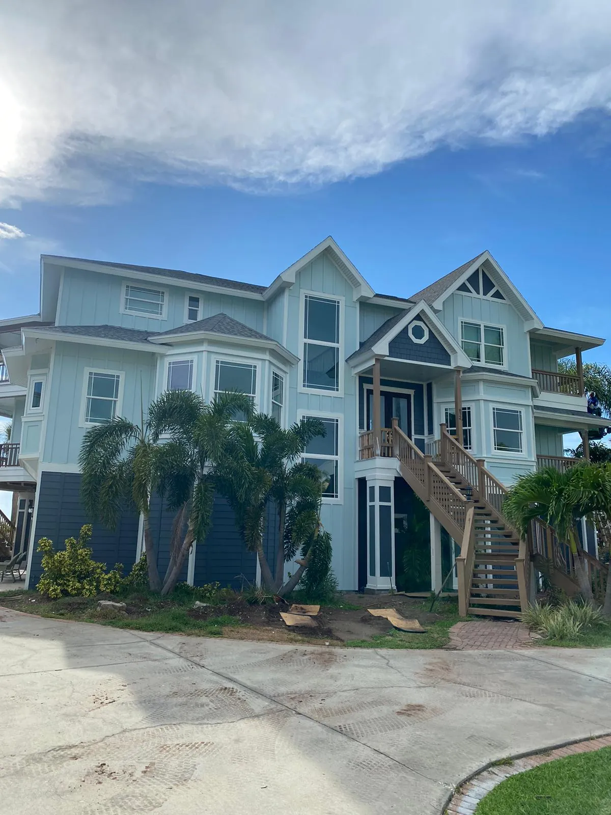 Freshly painted light-blue coastal home with white trim and a covered entry staircase